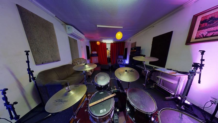 Sala de ensaio do Coruja Estúdio, com bateria e luz roxa