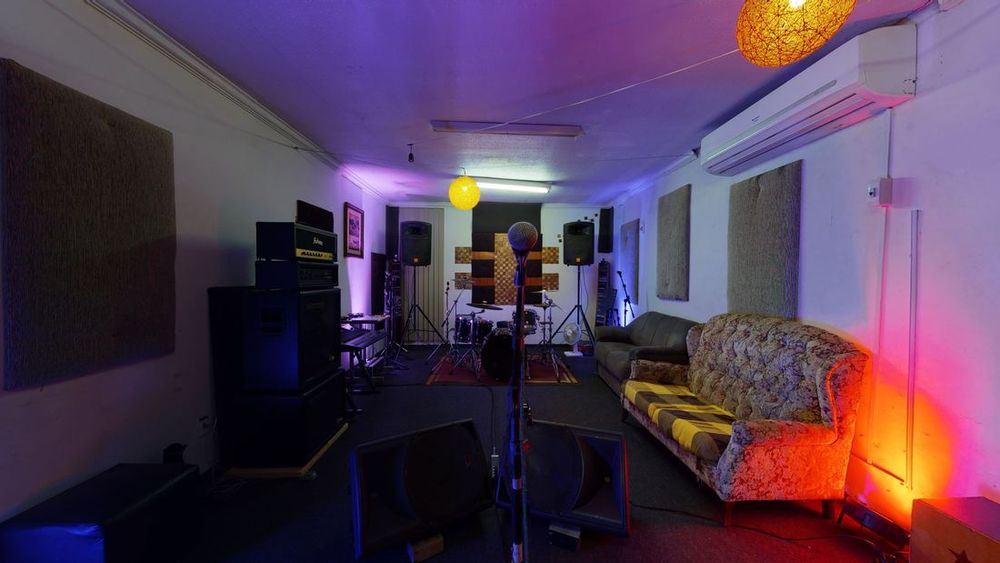 Sala de ensaio do Coruja Estúdio com luz roxa e sofá