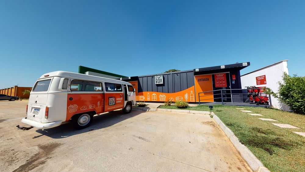 Fachada da Superbox vista da rua, com uma Kombi estacionada em frente