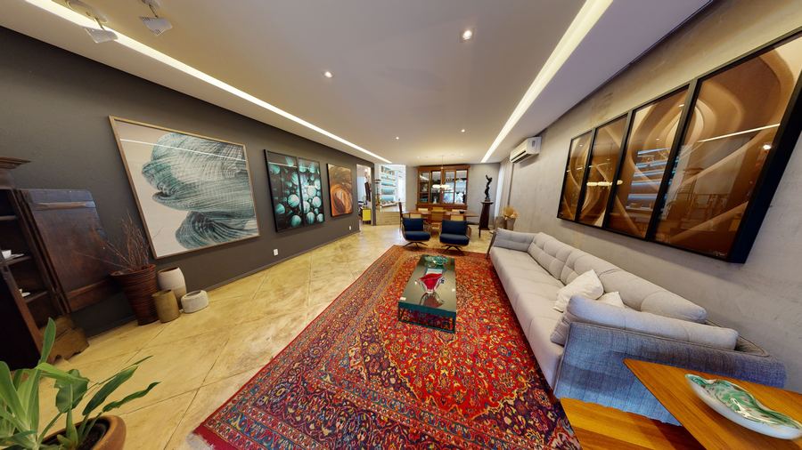 Sala de estar com tapete persa, sofá branco e quadros