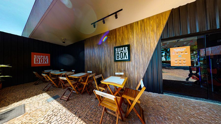 Fachada da Superbox, com mesas na calçada e letreiro
